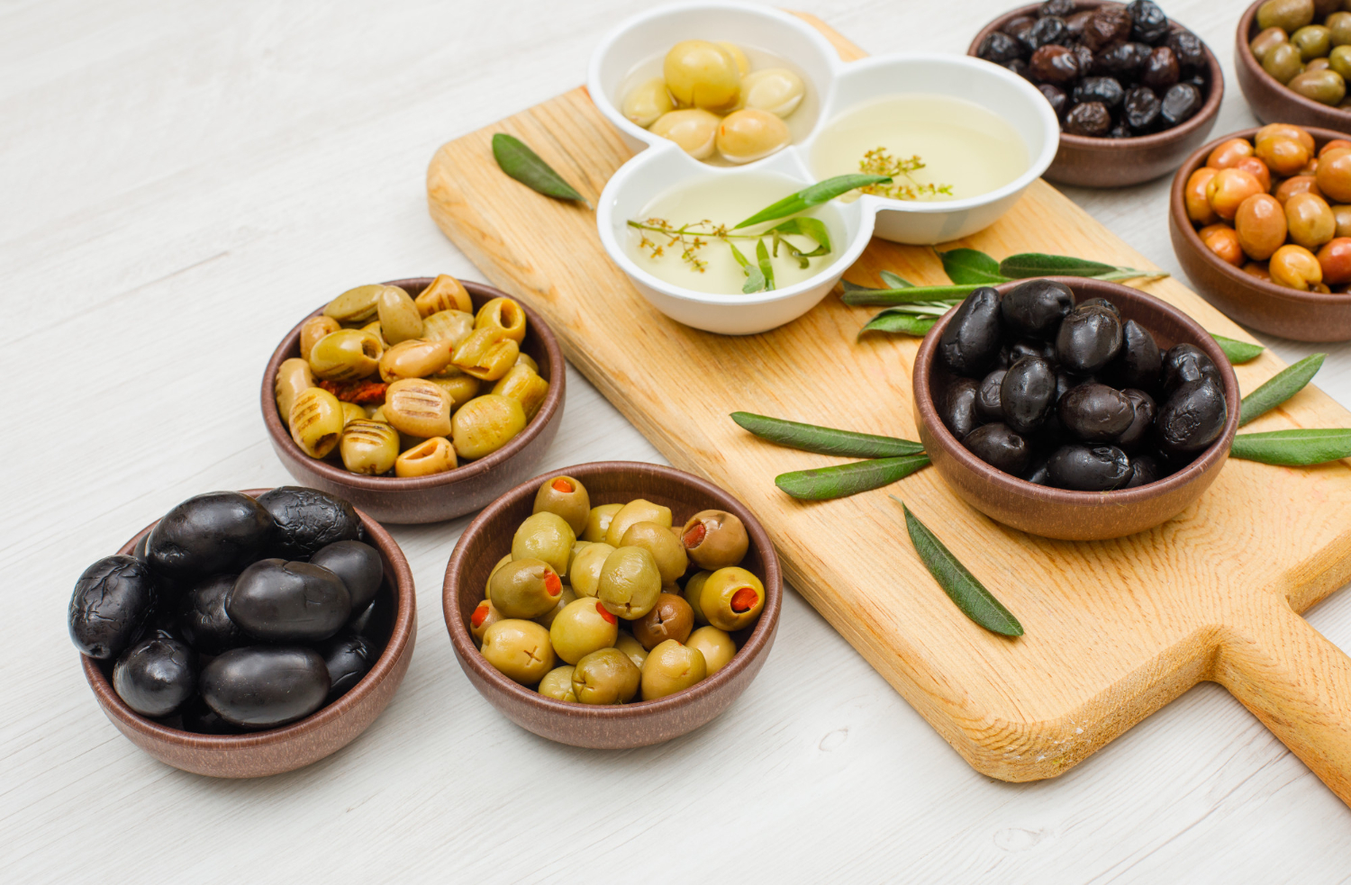 marinated olives olive oil with olive leaves bowls cutting board white wood high angle view - اسرار تفسير الاحلام